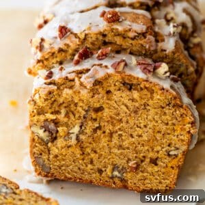 overhead view of a sliced loaf of butternut squash bread topped with a white glaze and pecans.