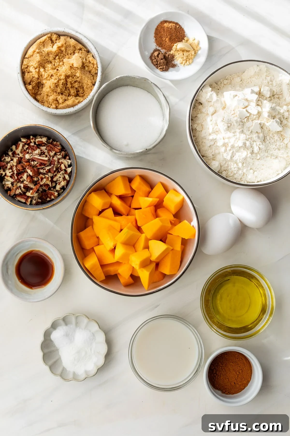 ingredients for butternut squash bread displayed in individual small bowls, showcasing fresh squash, various spices, and pecans.