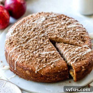 Round apple coffee cake with a sweet crumb topping, presented beautifully on a marble platter.