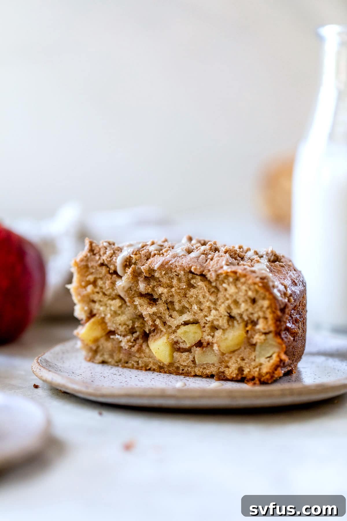 A beautifully cut slice of apple coffee cake, revealing the delicious layers of spiced apples and the crumbly topping.