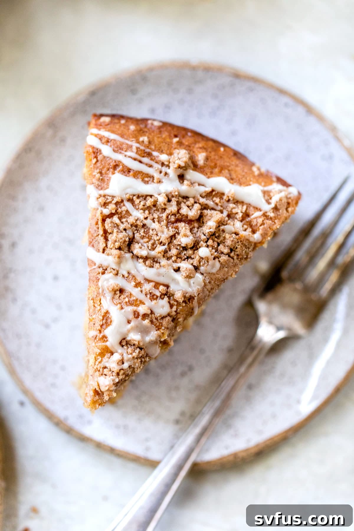 A perfectly sliced piece of apple coffee cake served on a small plate next to a fork, ready to be enjoyed.