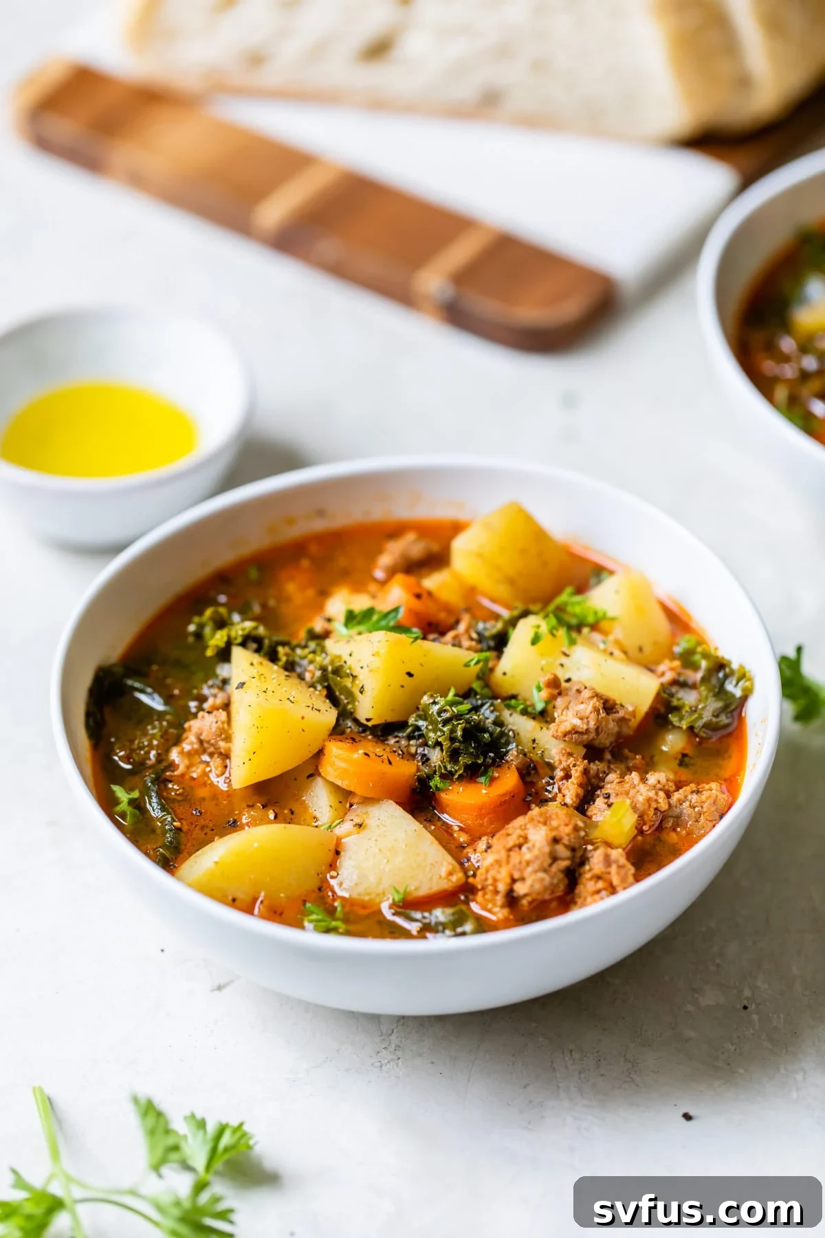 A beautifully presented bowl of Spicy Sausage Potato Soup on a rustic wooden table, garnished with fresh parsley.