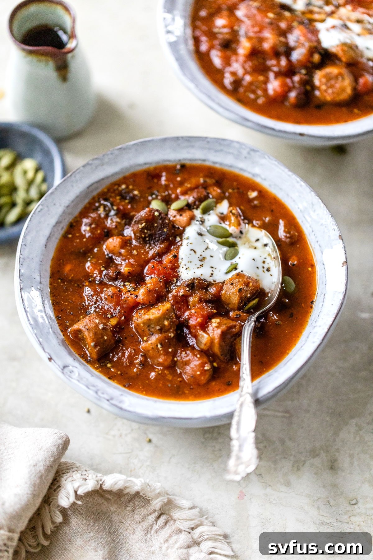 a bowl of pumpkin chili topped with sour cream and pumpkin seeds