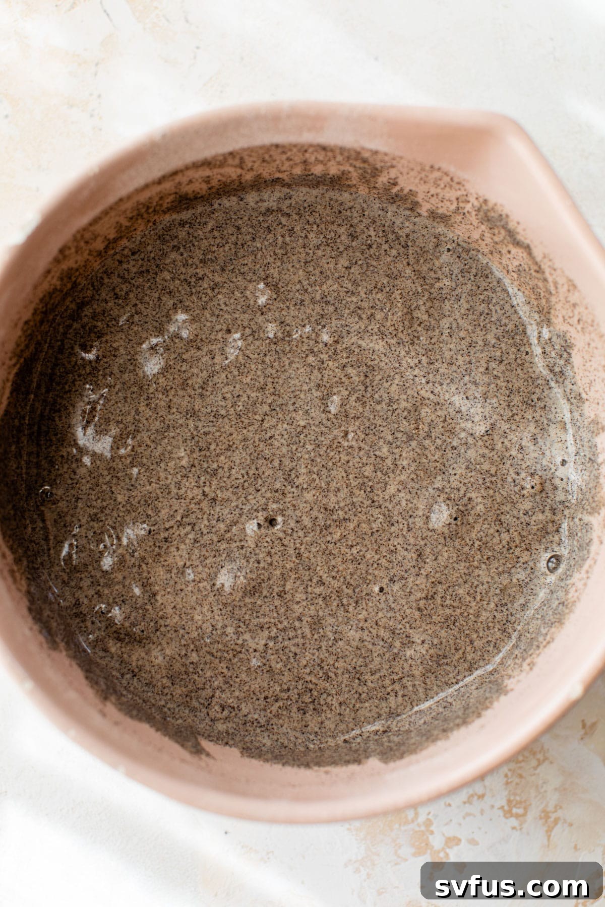 Pancake batter in a large mixing bowl, showing its dark color and consistency