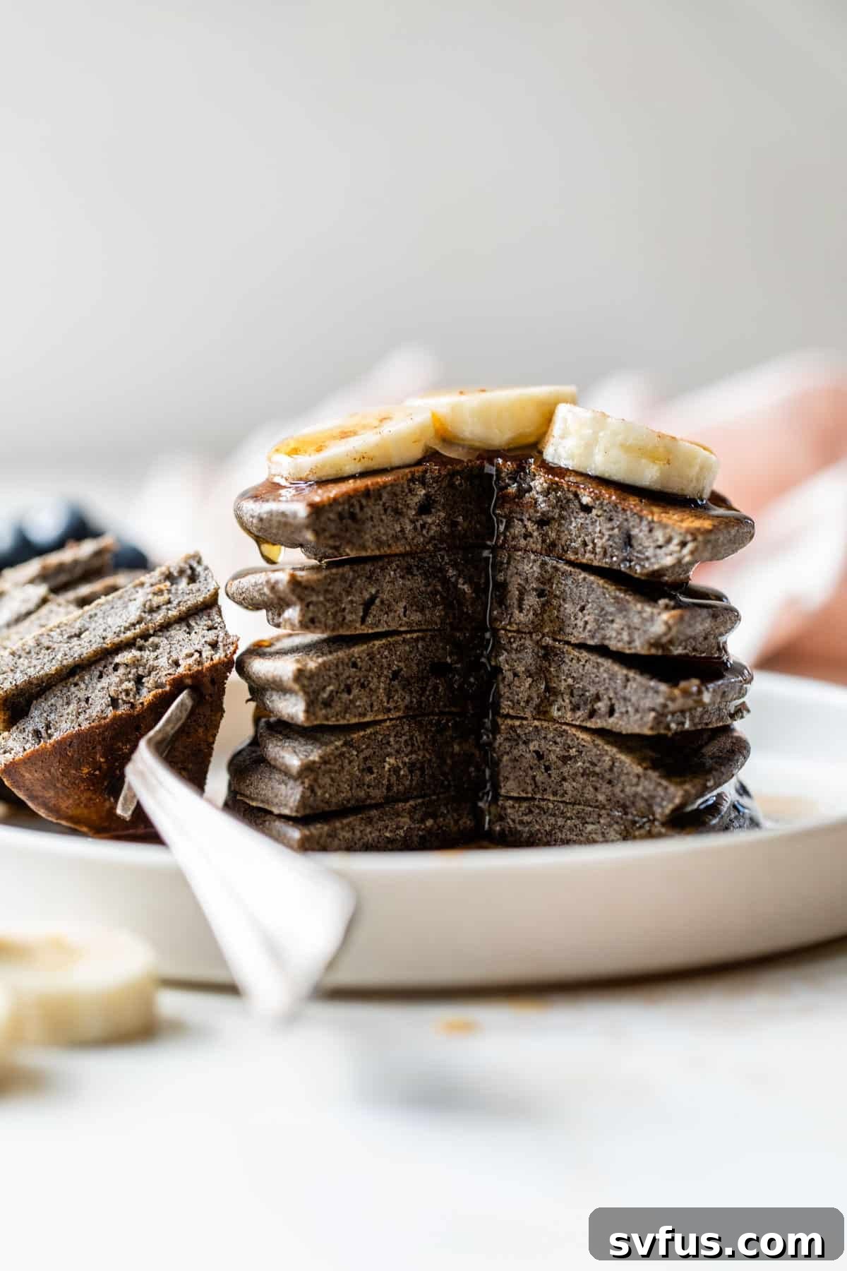 A side view of a stack of buckwheat pancakes with a bite taken out, showing the fluffy interior
