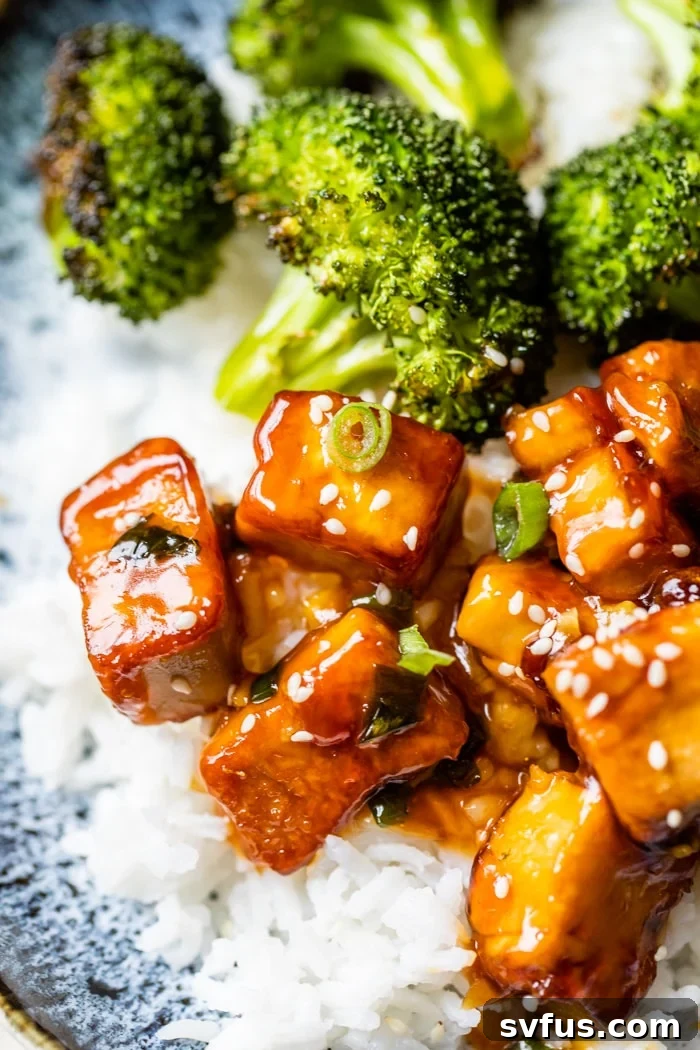 Close-up of crispy General Tso's Tofu served on a bed of rice with vibrant green broccoli florets