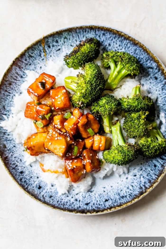 A serving of General Tso's Tofu, rice, and steamed broccoli neatly arranged on a white plate