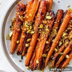 Vibrant roasted carrots adorned with a maple glaze and chopped pistachios on an elegant serving plate.
