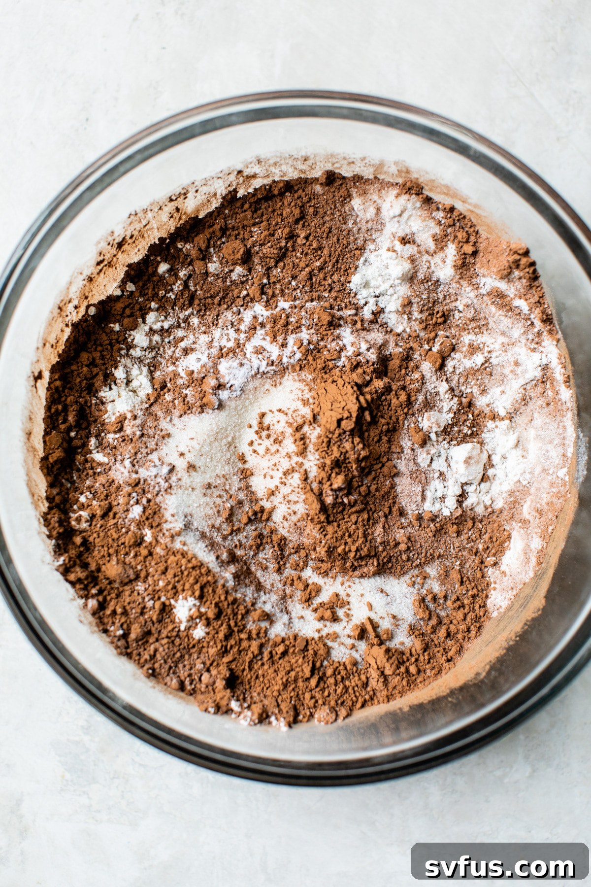 Close-up of cocoa powder being added to a bowl of dry cake ingredients, ready for mixing.
