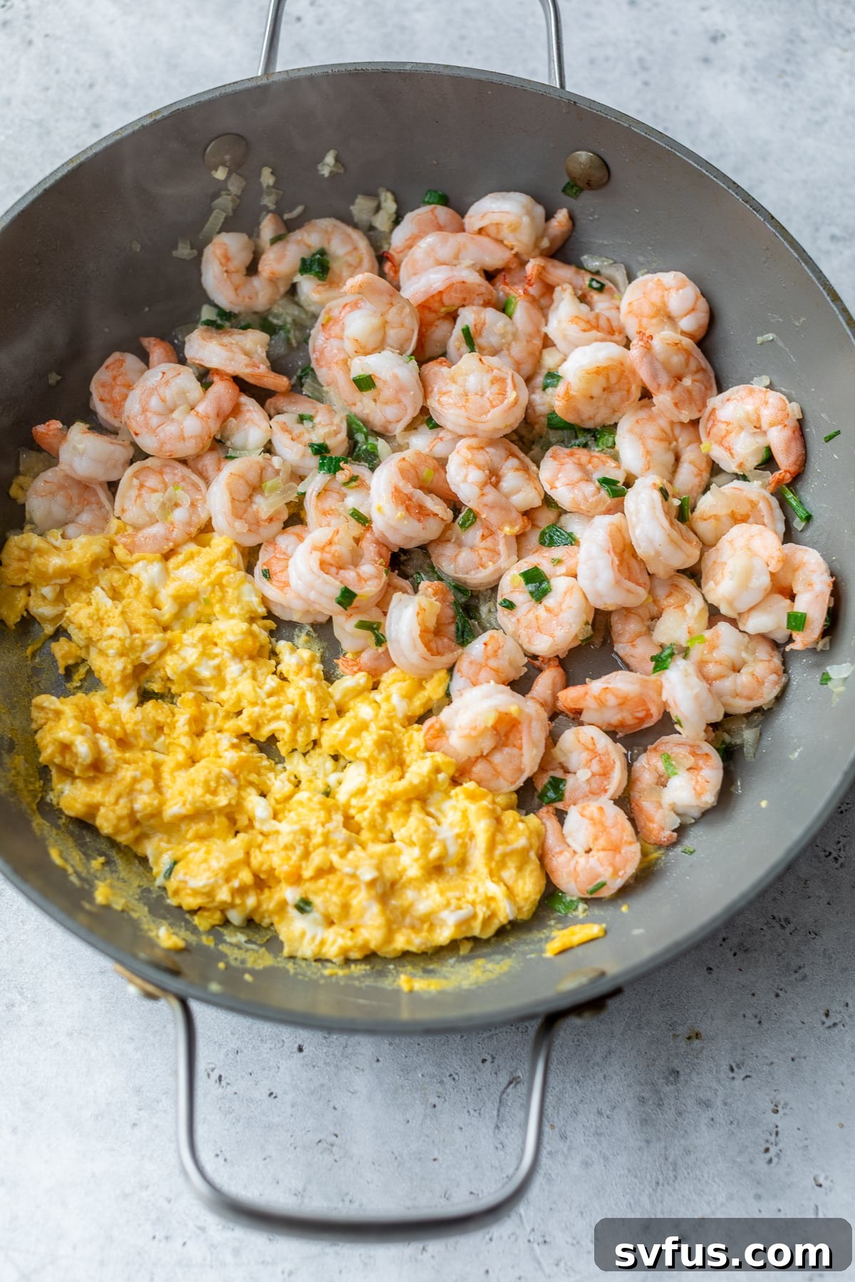 Shrimp and scrambled eggs combined in a skillet, showcasing the vibrant colors of the ingredients.
