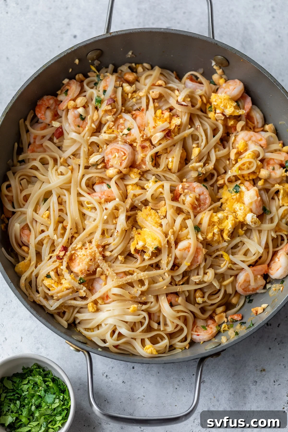 A large skillet brimming with freshly tossed Shrimp Pad Thai, ready to be portioned.