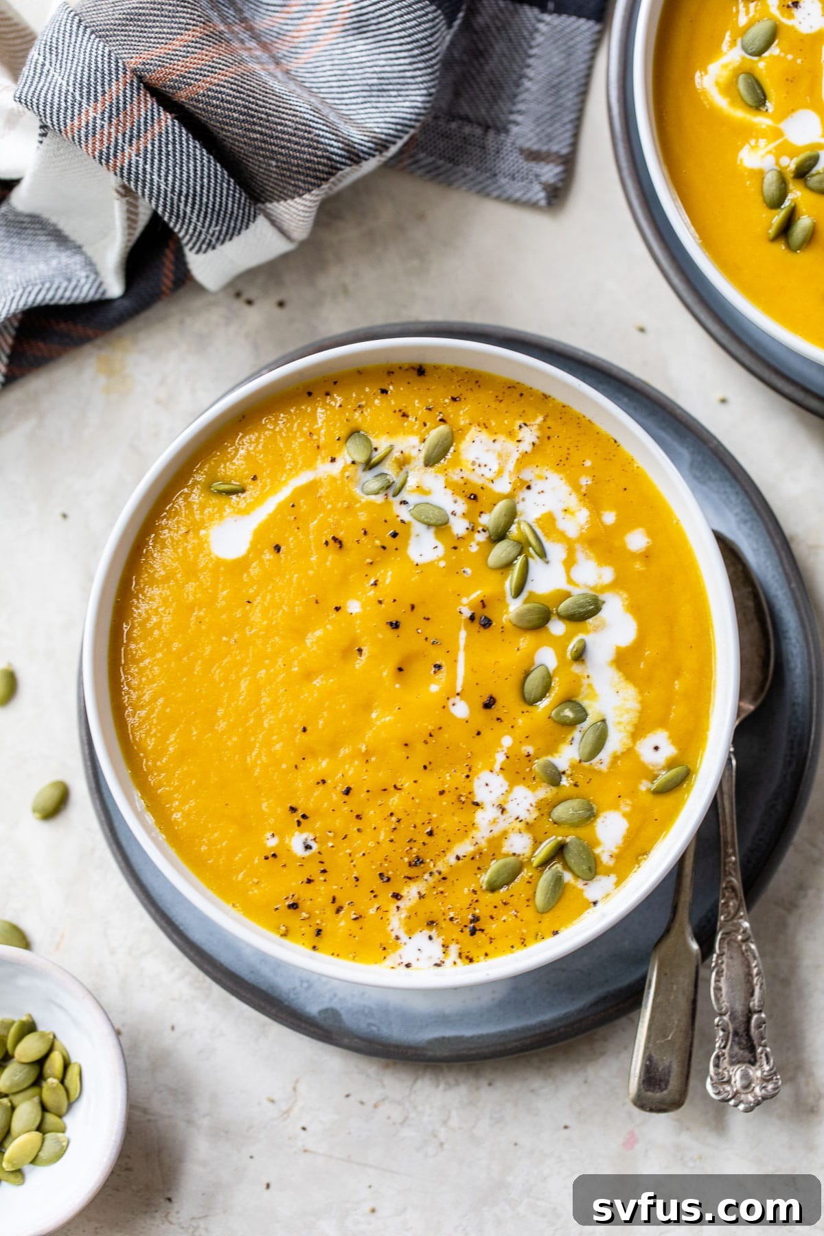 A bowl of creamy, blended Slow Cooker Pumpkin Curry Soup, beautifully topped with a swirl of coconut milk and a handful of pumpkin seeds, ready for a comforting meal.