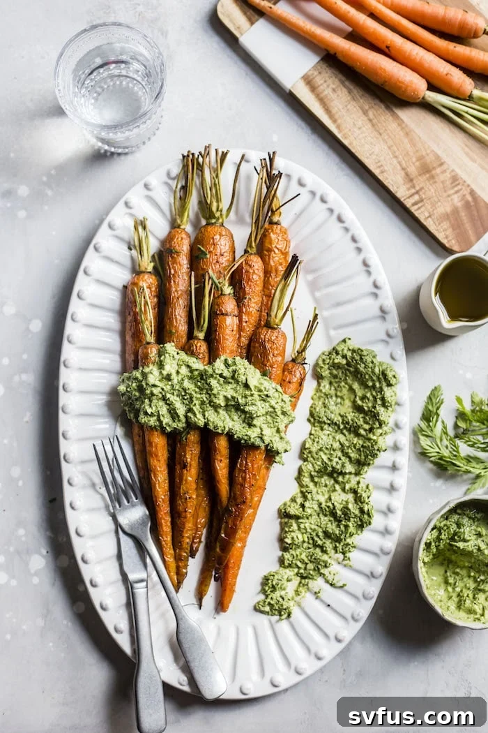 Perfectly Roasted Carrots with a vibrant green Tarragon Carrot Top Pesto drizzled over them. The dish is presented beautifully on a white plate, highlighting the fresh, natural ingredients.