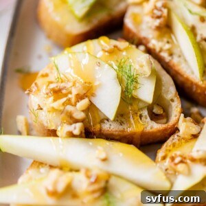 a small slice of bread on a plate topped with pears, walnuts and honey