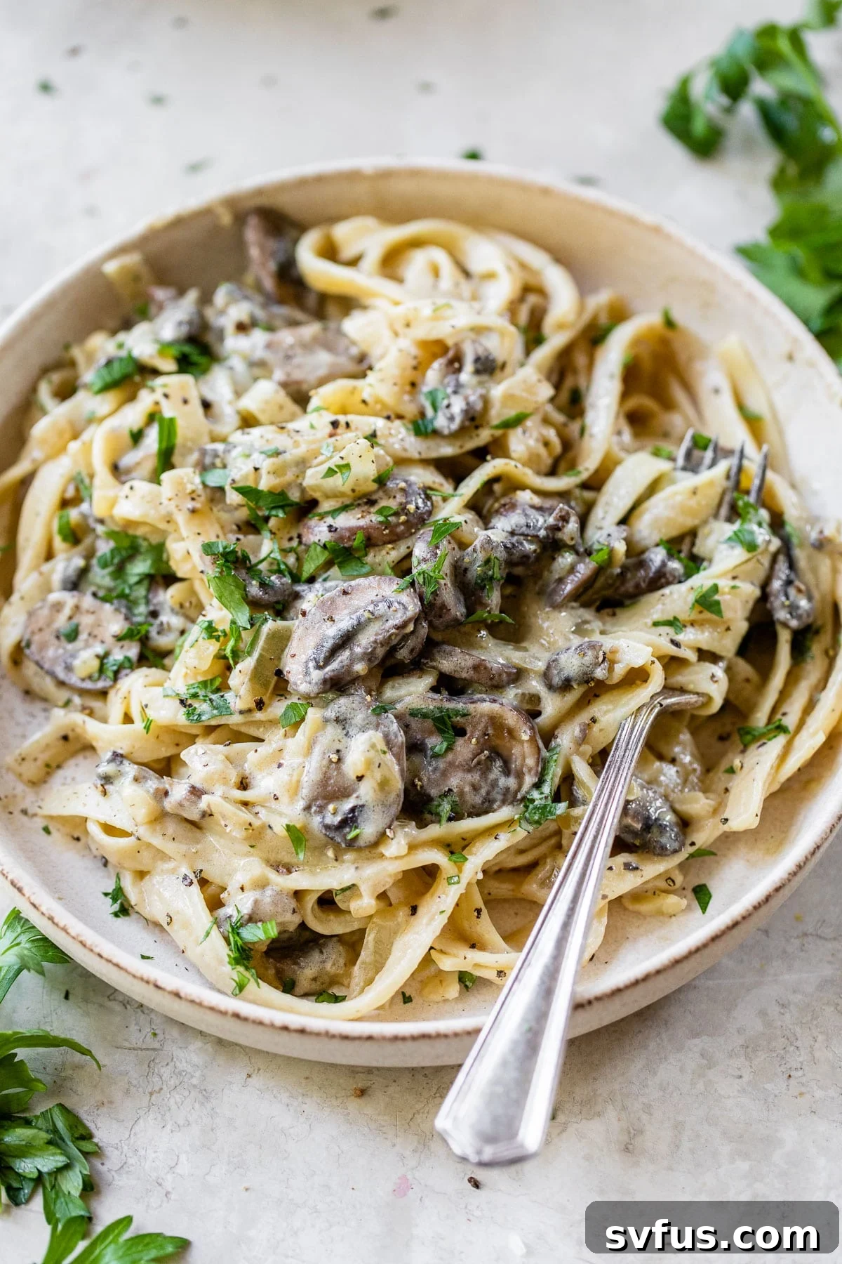 A close-up shot of creamy vegan mushroom pasta served in a white bowl, garnished with fresh parsley.