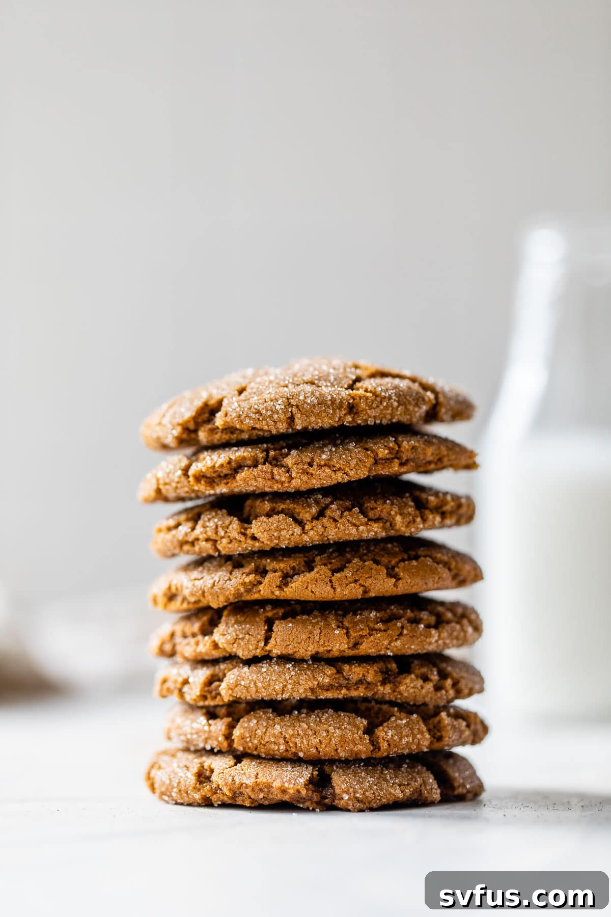 A tempting stack of freshly baked vegan ginger cookies presented alongside a tall glass of plant-based milk, inviting indulgence.