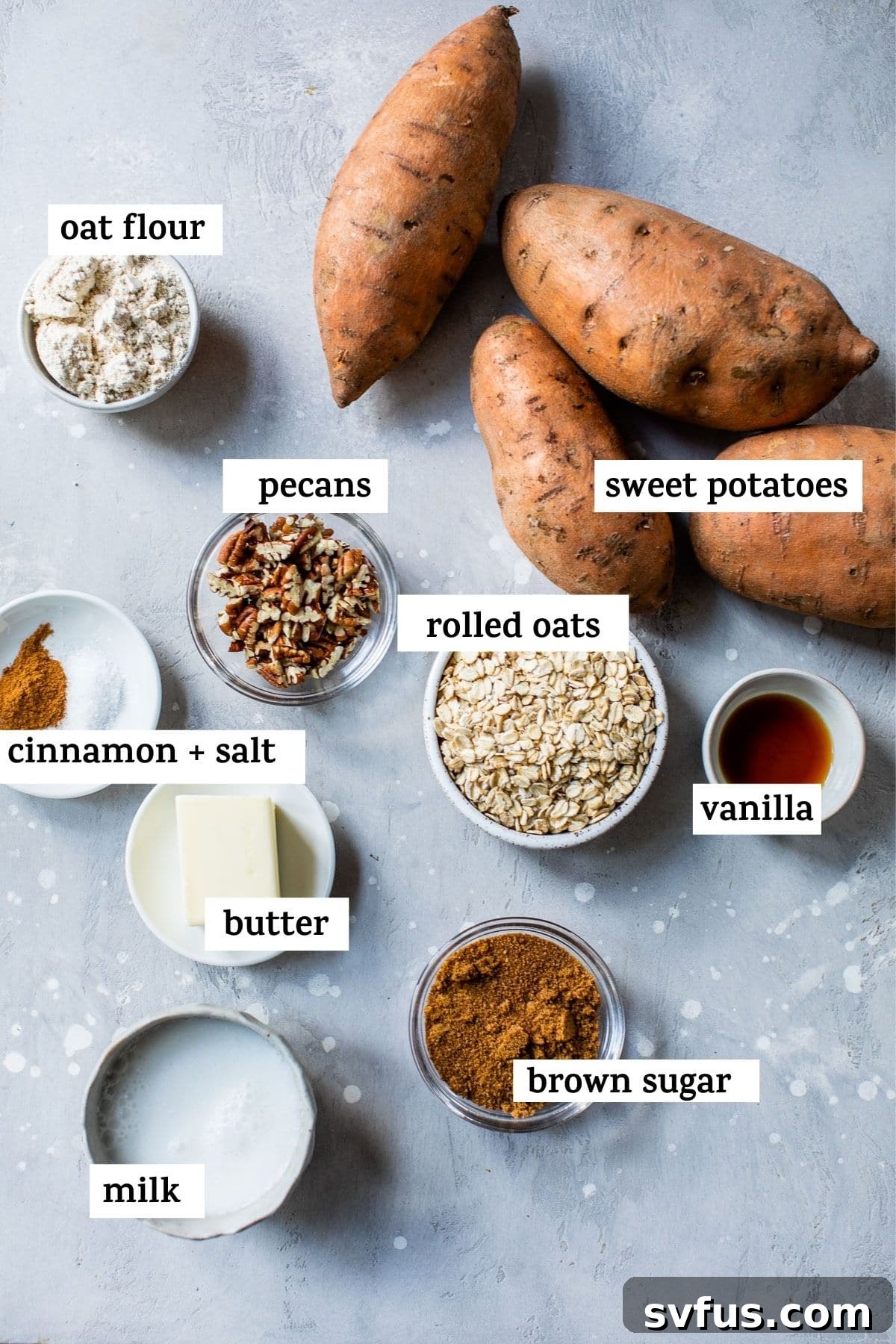 Various fresh ingredients laid out on a white surface, including sweet potatoes, oats, pecans, brown sugar, and spices, ready for cooking.
