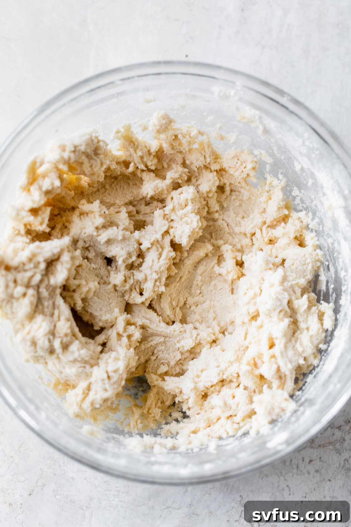 Cookie dough resting in a large glass bowl, chilling in the refrigerator.