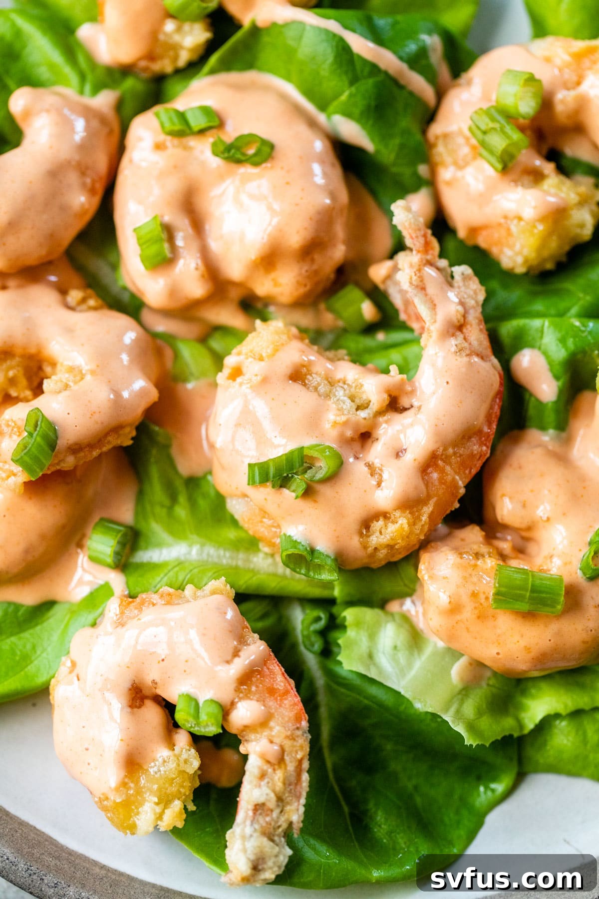fried shrimp coated in bang bang sauce on top of butter lettuce