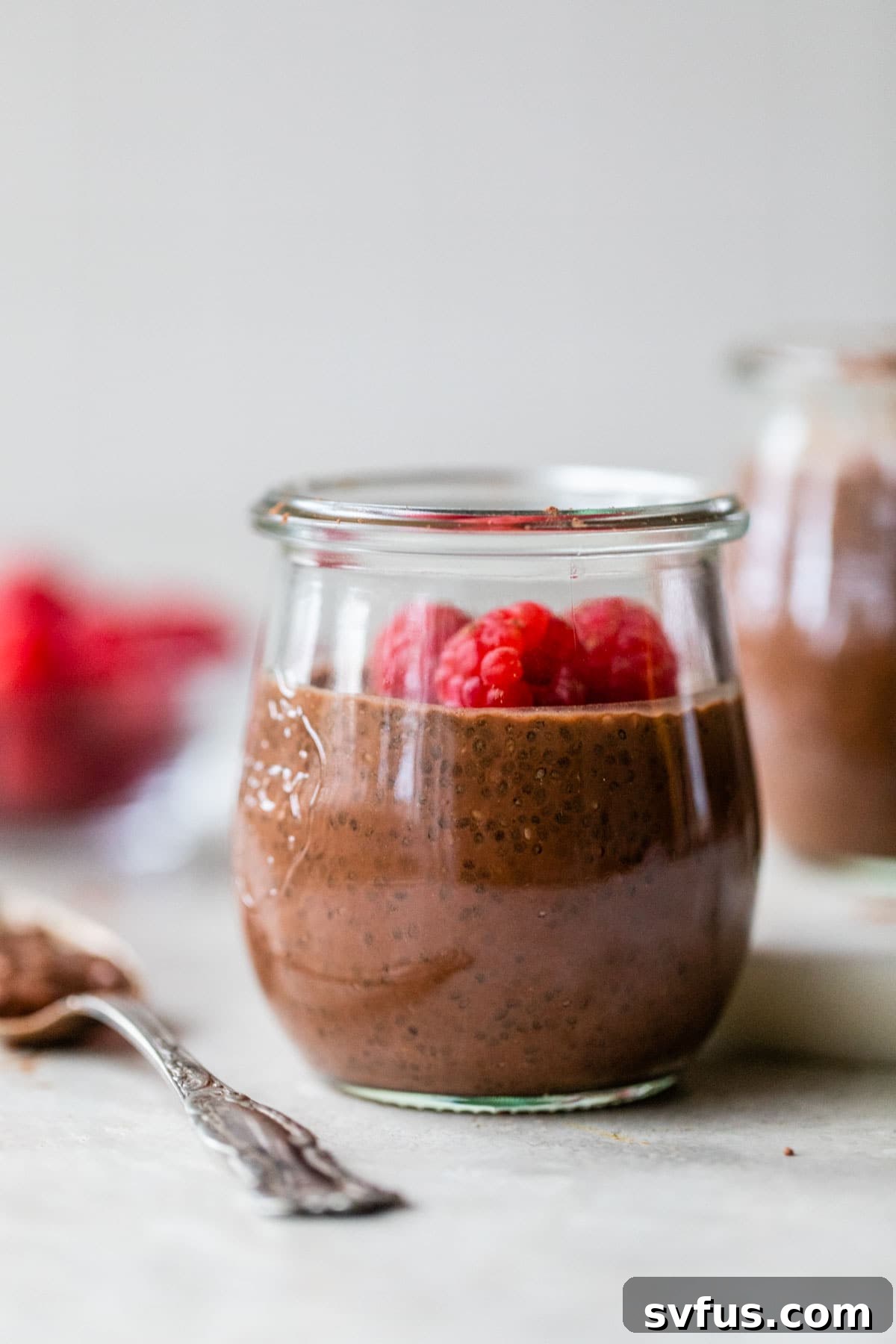 small jar filled with chocolate milk, chia seeds and raspberries