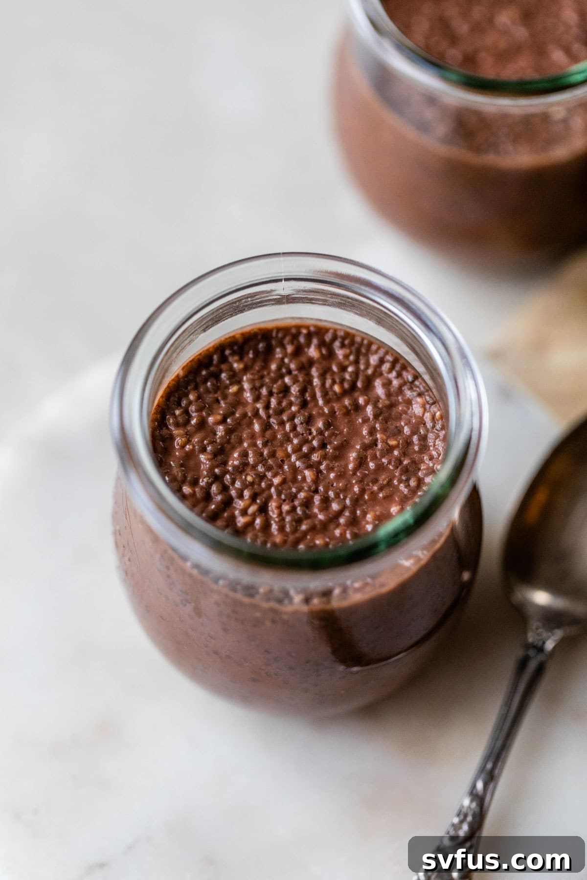 chocolate chia pudding in a glass jar with a spoon beside it