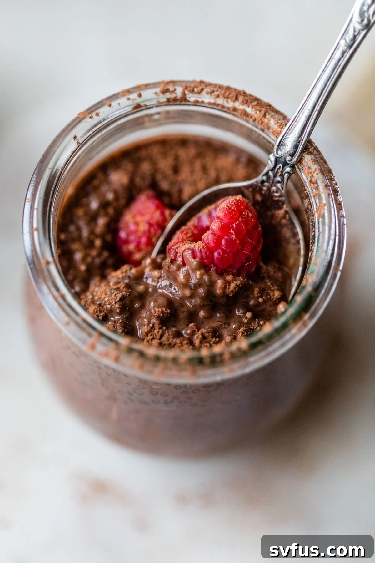 glass jar filled with chia pudding topped with raspberries