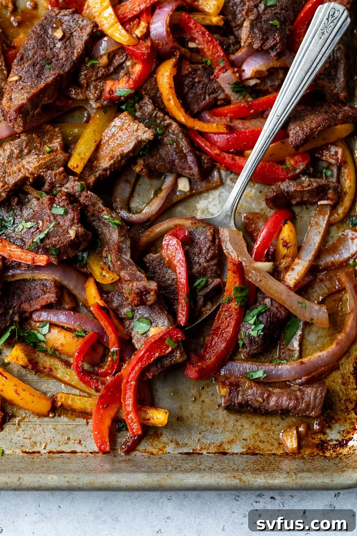 Vibrant sheet pan fajitas, featuring seasoned flank steak, colorful bell peppers, and onions, fresh from the oven and ready to serve.