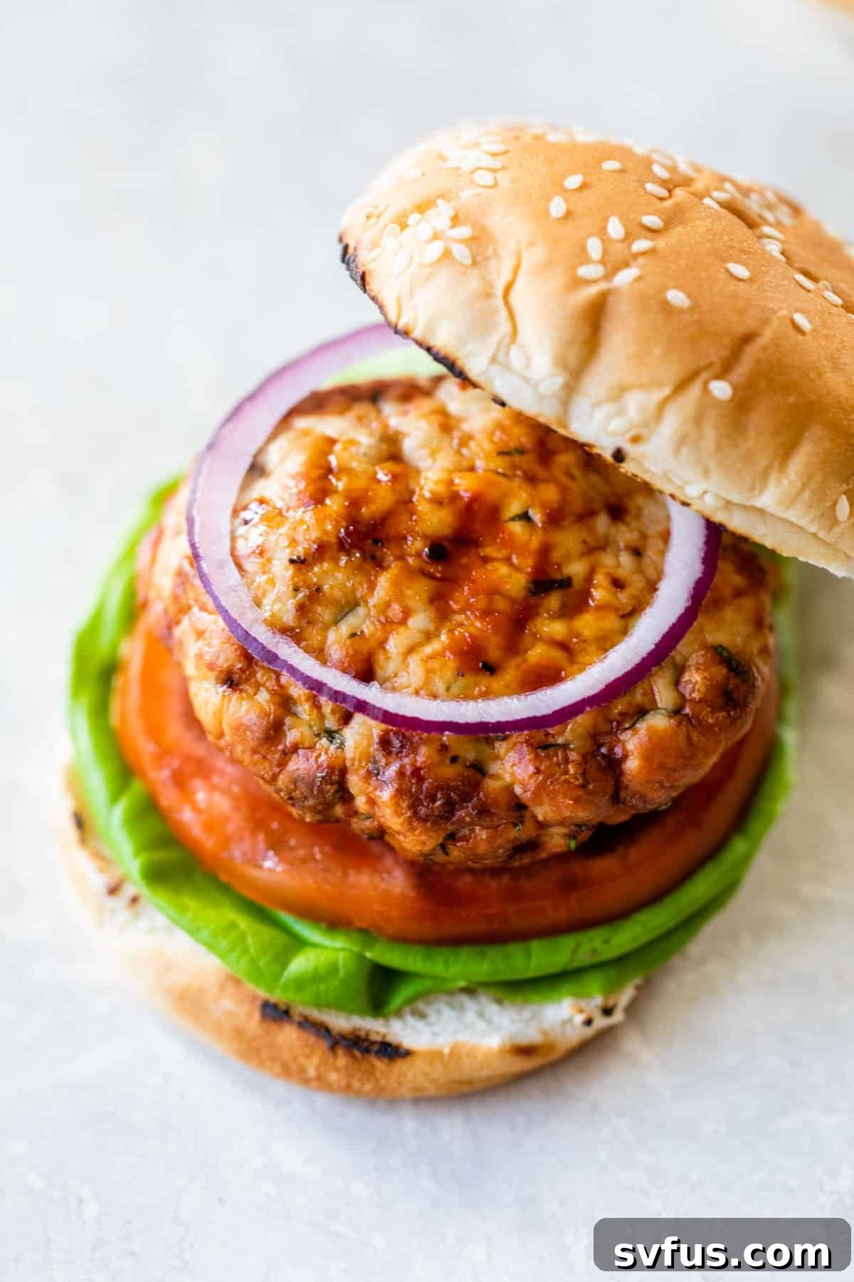 A perfectly cooked turkey burger, served on a soft bun with crisp lettuce, juicy tomato slices, and rings of red onion.