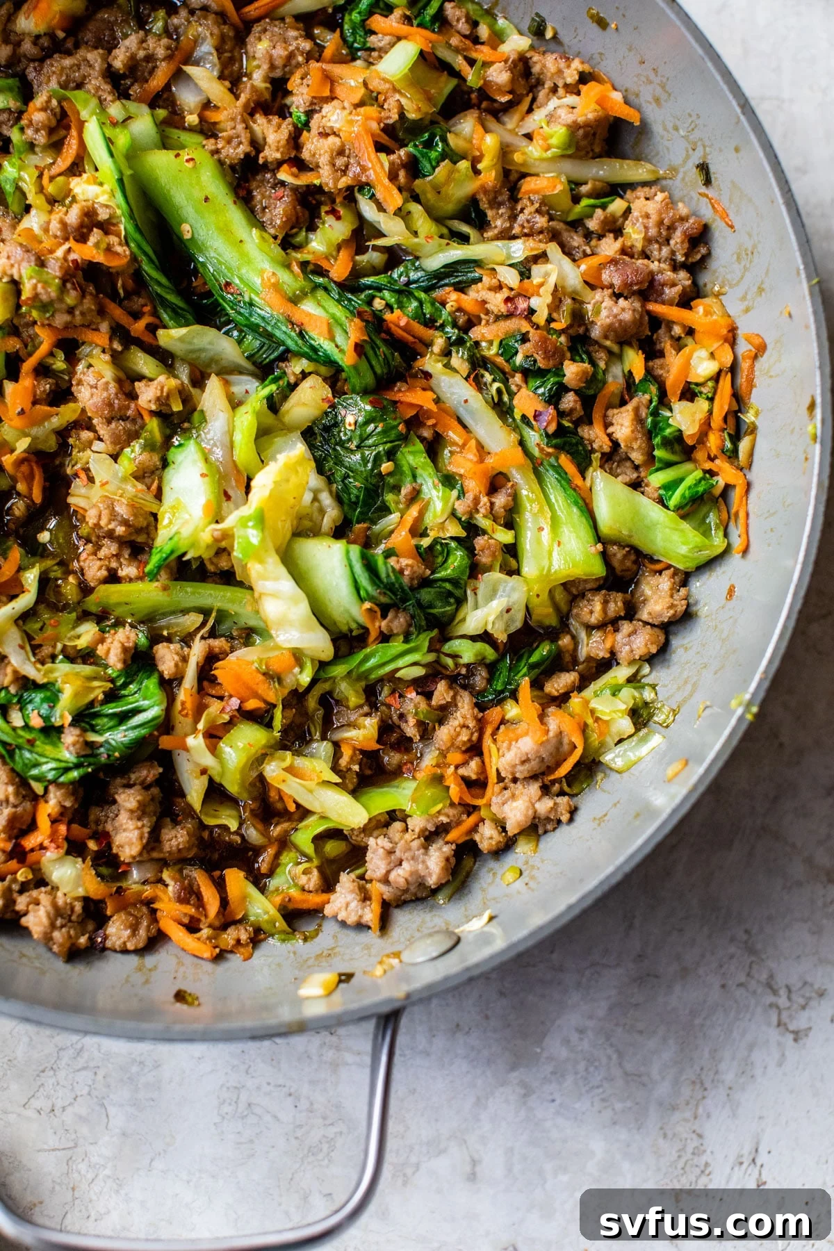 A colorful and savory stir-fry, featuring seasoned ground pork and a medley of fresh vegetables, served hot in a skillet.