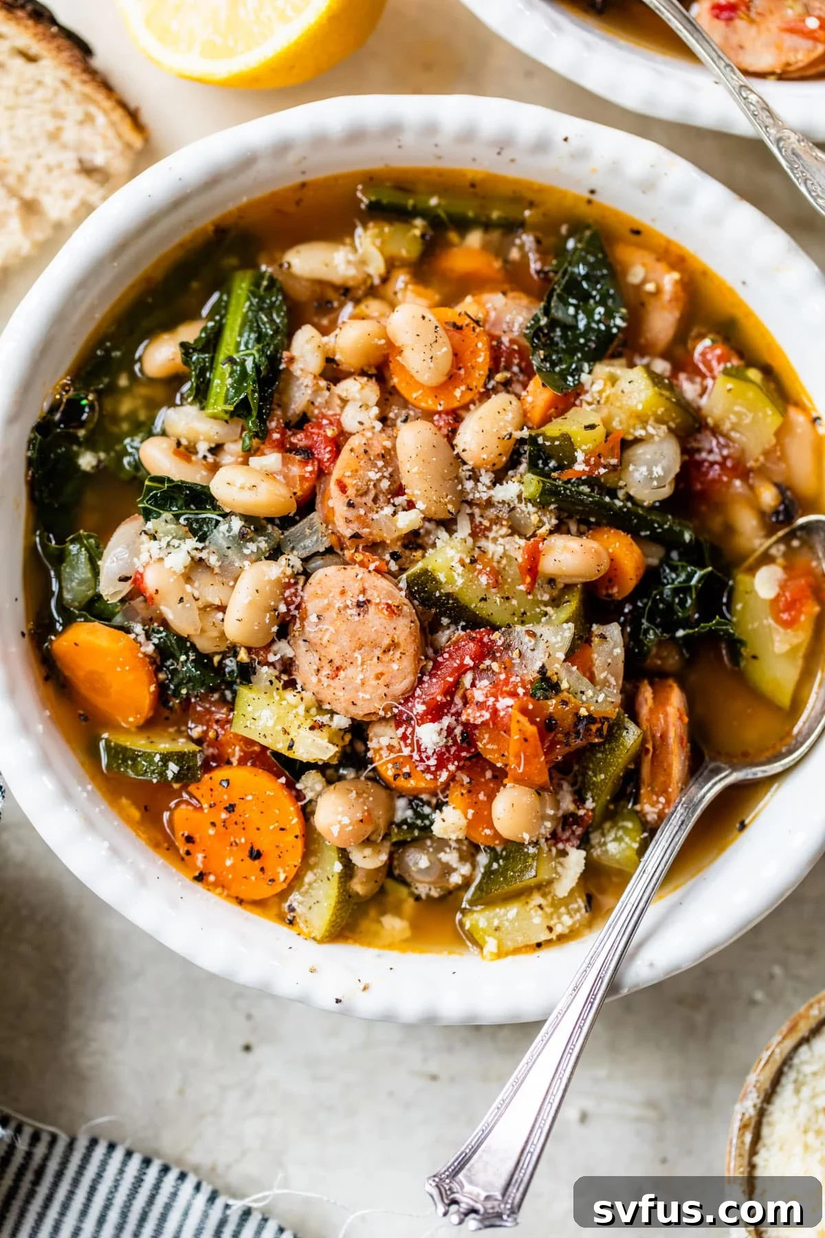 A hearty and wholesome bowl of soup, featuring savory chicken sausage, tender beans, and vibrant kale, all in a rich broth.