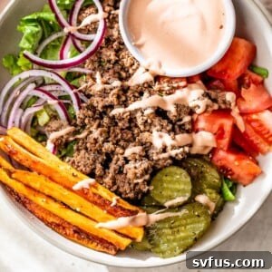 bowl filled with lettuce, ground beef, sweet potato, tomato and pickles