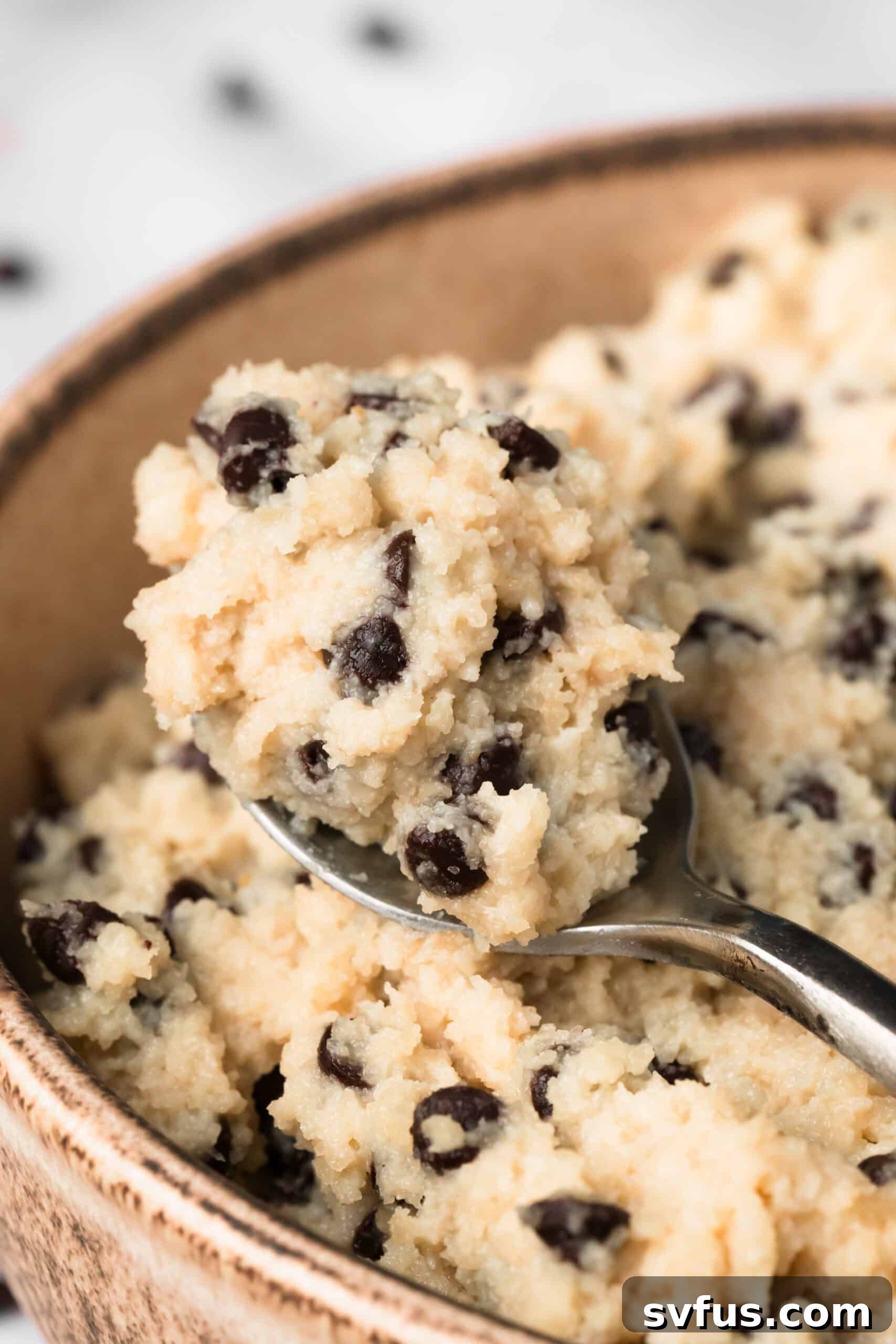 Close up on a spoonful of chocolate chip cottage cheese cookie dough in a bowl.