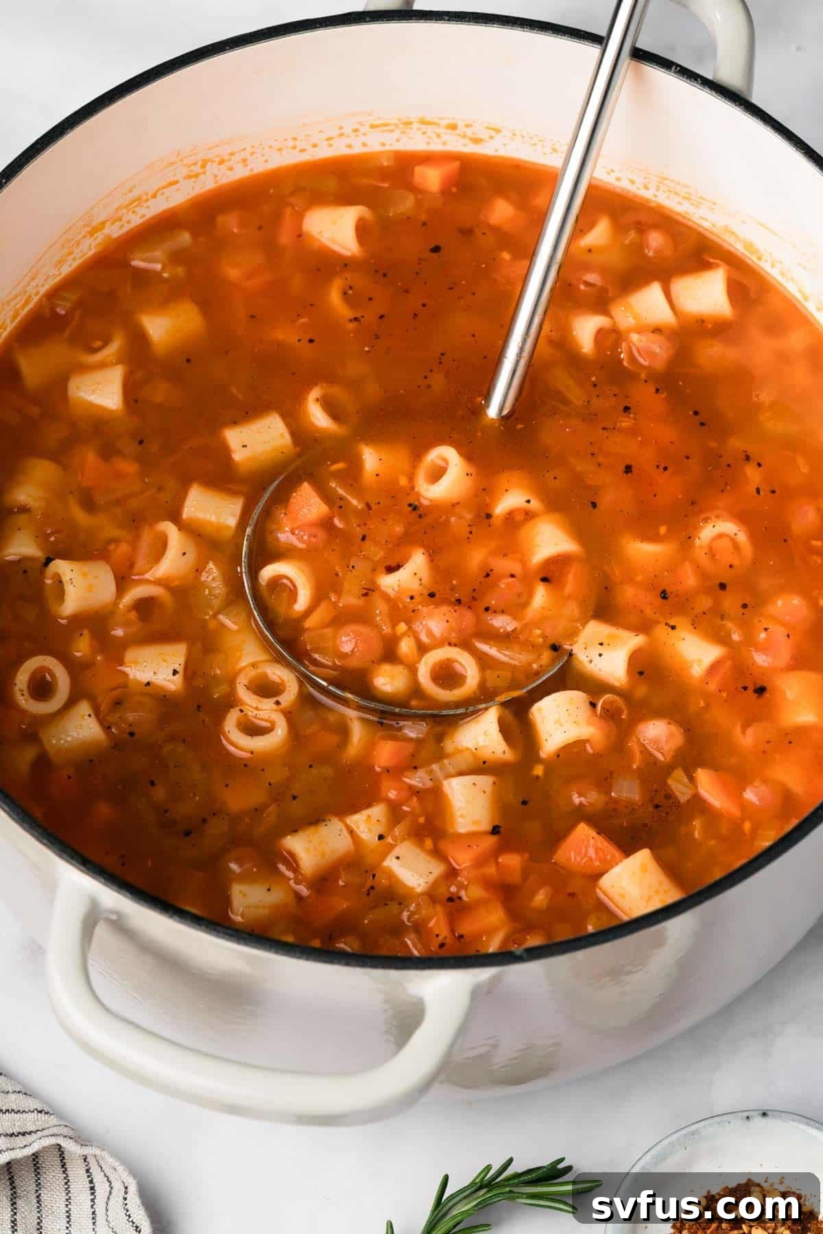 Side view of a large pot filled with the finished, thick and steaming Pasta e Ceci.