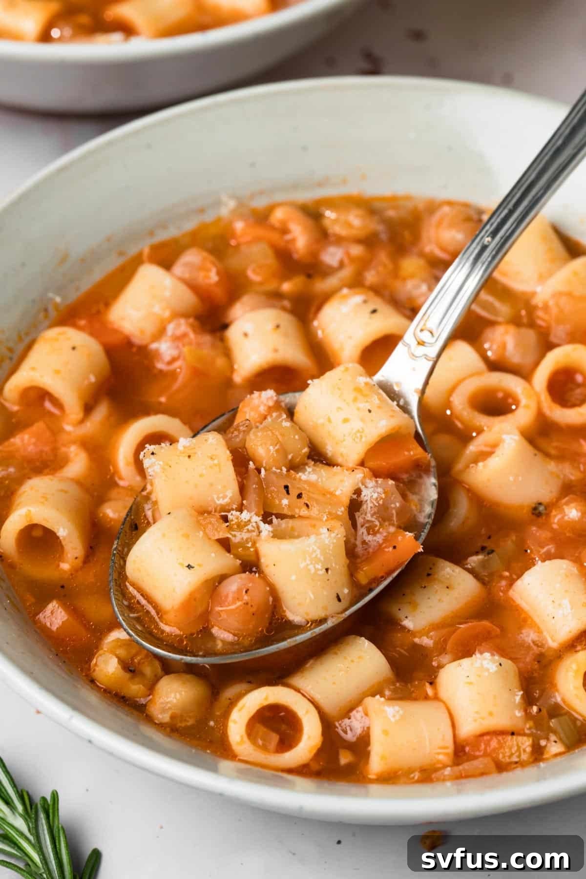 Close-up on a spoonful of thick Pasta e Ceci being lifted from a bowl, highlighting its creamy texture.