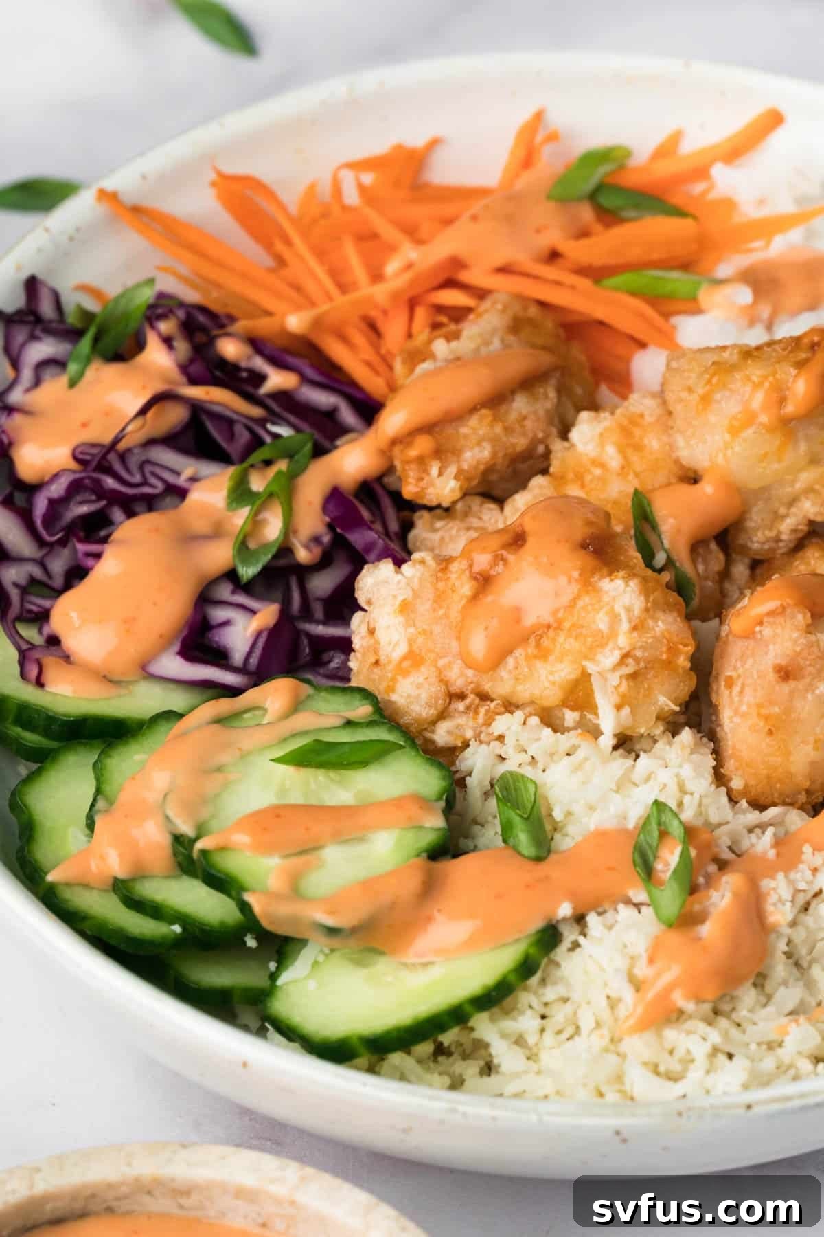 A vibrant Bang Bang Chicken Bowl, showcasing crispy chicken, colorful vegetables, and a creamy sauce drizzled over rice.