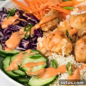 Side view of a perfectly plated Bang Bang Chicken Bowl, highlighting the crispy chicken and fresh toppings.