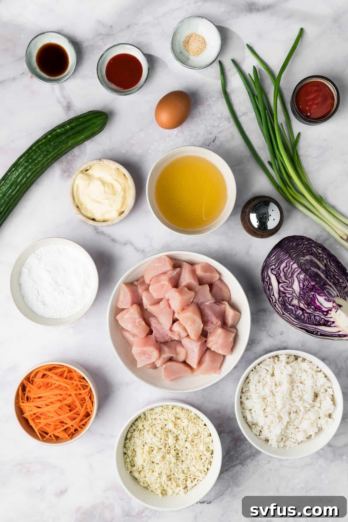 An overhead view displaying all the fresh ingredients for Bang Bang Chicken Bowls, neatly arranged in separate small bowls.