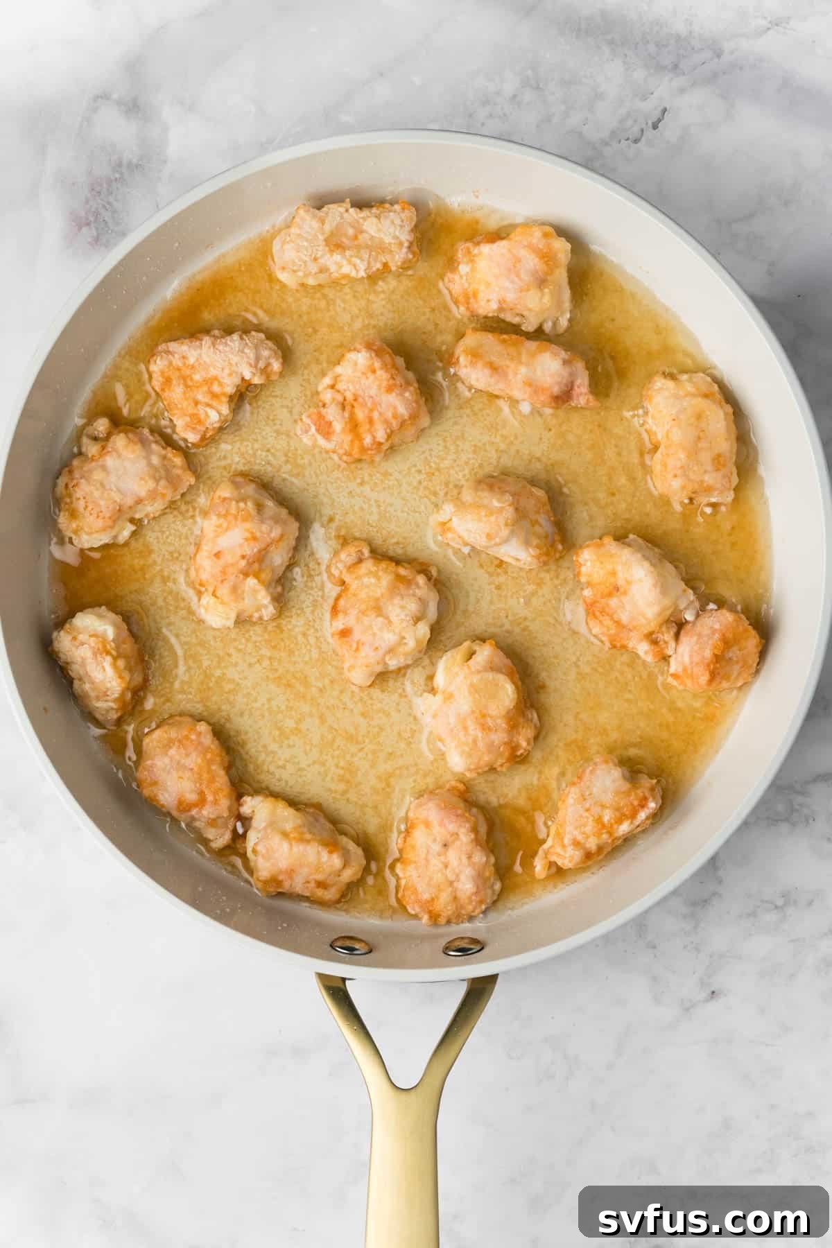 Golden-brown, crispy chicken pieces frying evenly in a hot skillet, almost ready to be removed.