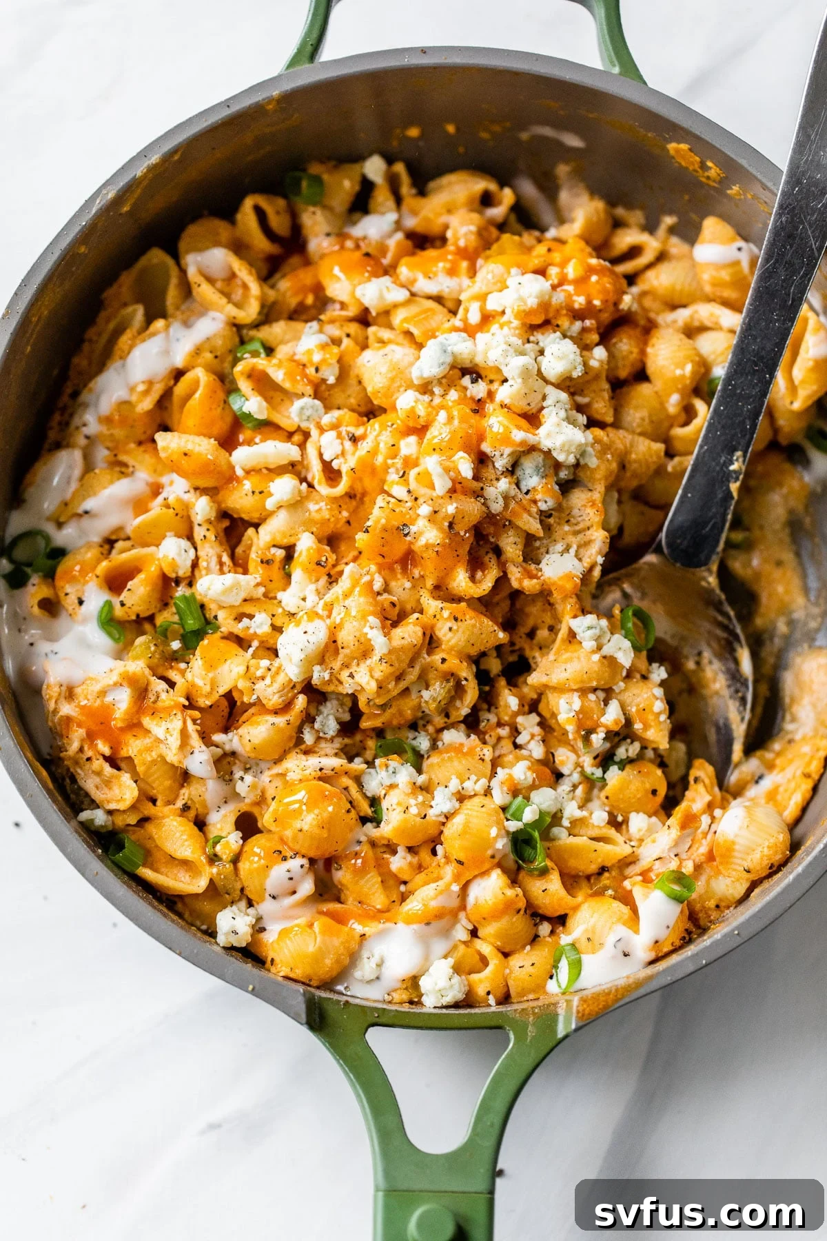 A vibrant skillet filled with al dente pasta and tender chicken, all tossed in a fiery buffalo sauce for a spicy, satisfying meal.