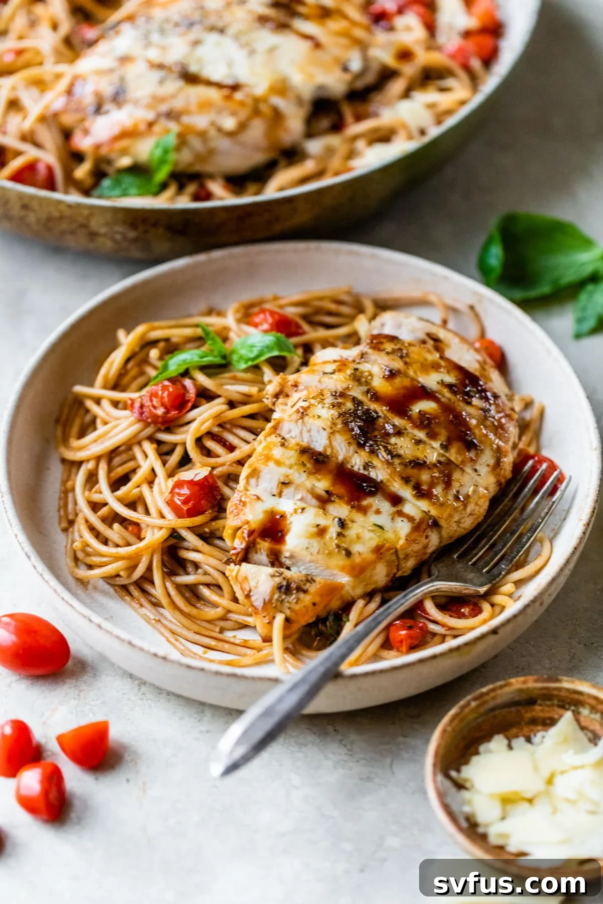 A delectable serving of bruschetta chicken pasta on a plate, garnished with fresh basil leaves and a fork, inviting you to dig in.