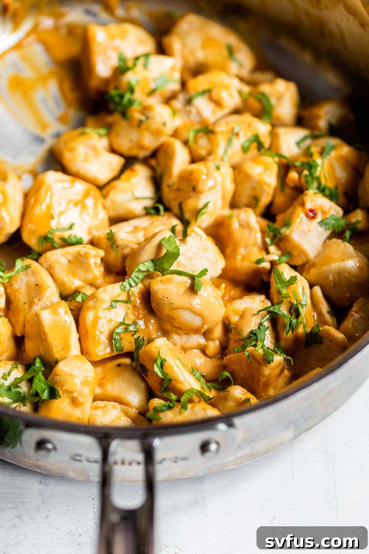 Marinated diced chicken sizzling in a skillet, beautifully sprinkled with fresh cilantro for a vibrant finish.