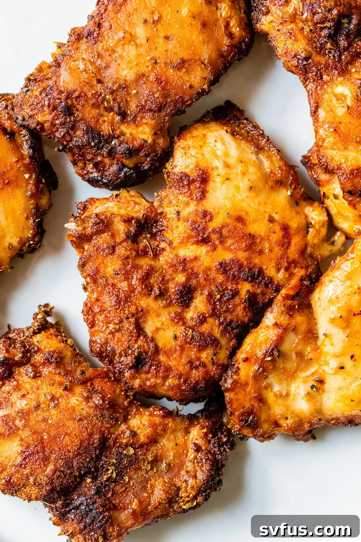 Perfectly crispy, golden-brown chicken thighs served on a white plate, showcasing their inviting texture.