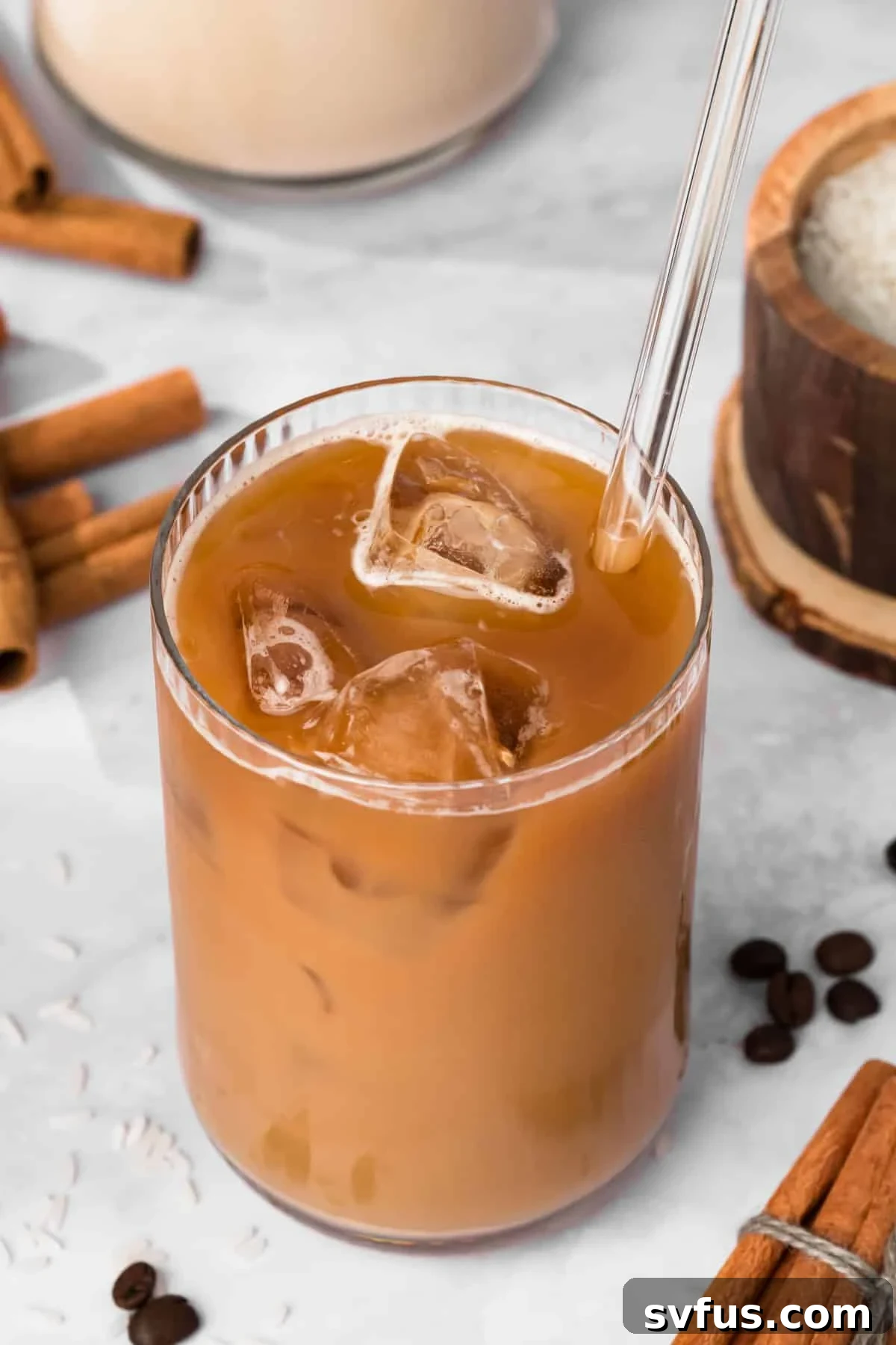 Overhead view of a beautifully prepared iced horchata latte in a clear glass, garnished with a sprinkle of cinnamon.
