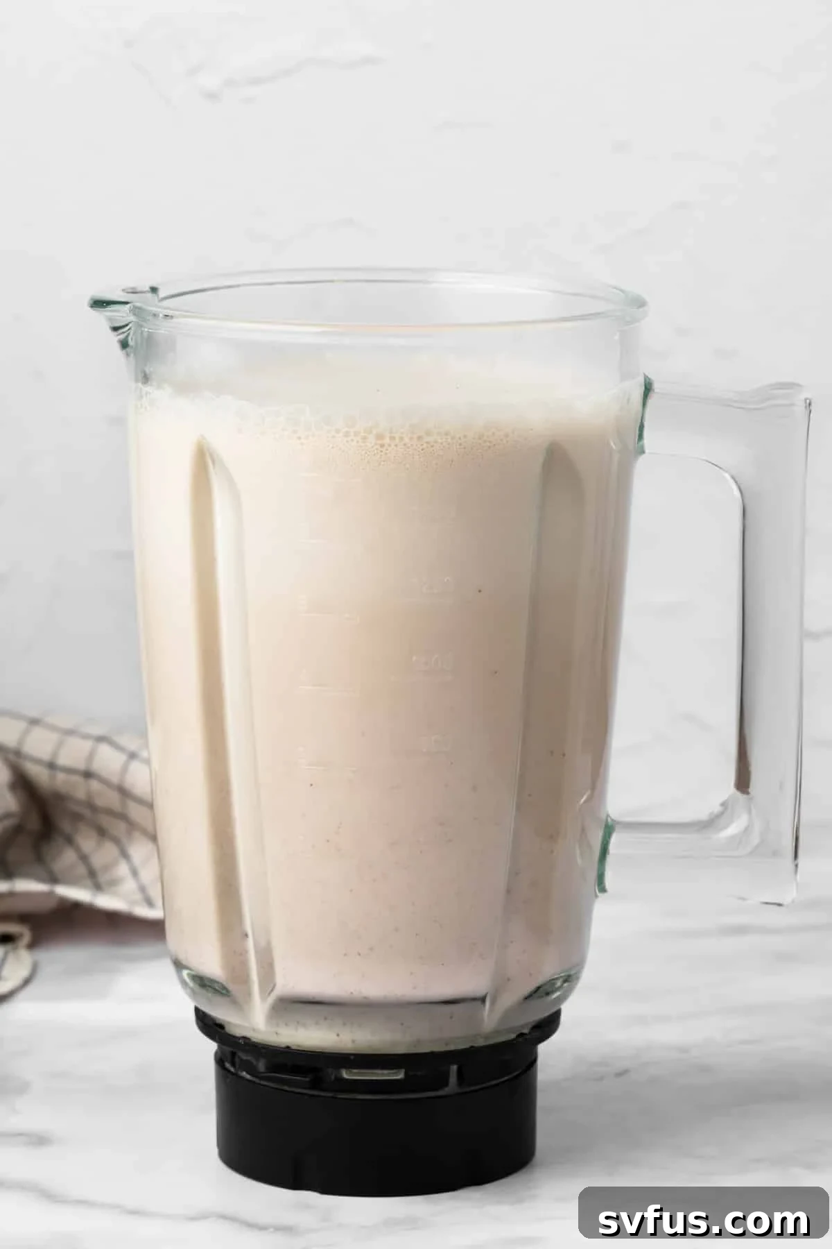 Side view of the blended horchata mixture in a large blender, now a smooth, milky liquid.