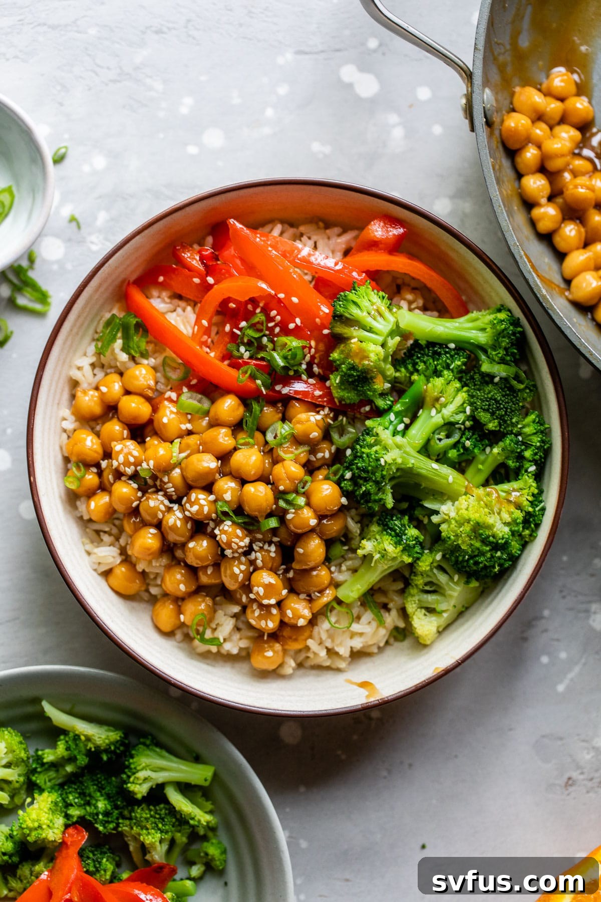 Two bowls featuring General Tso's Chickpeas, served with rice, broccoli, and bell pepper.