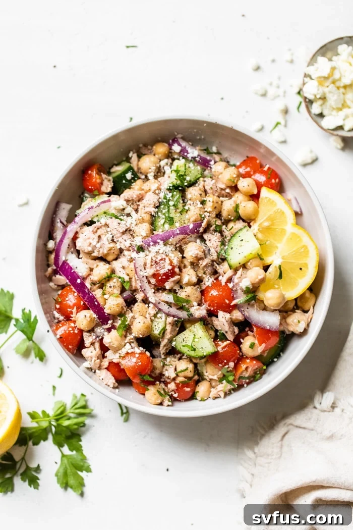 A bowl of Mediterranean Chickpea Tuna Salad, featuring chickpeas, tuna, tomatoes, and cucumbers.