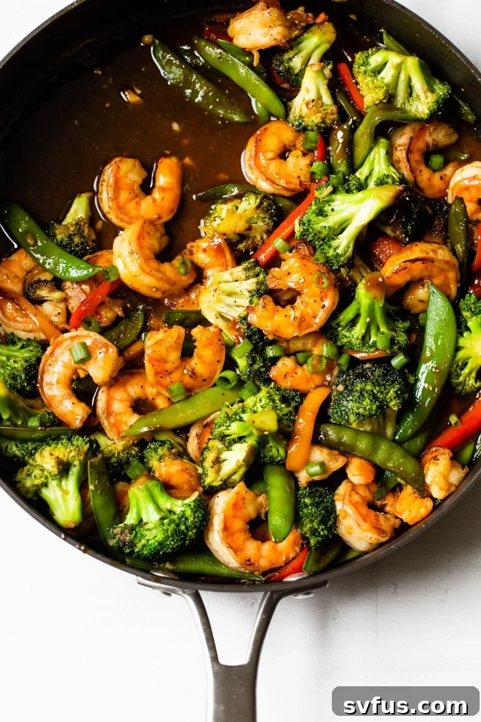 A skillet filled with Honey Garlic Shrimp Stir Fry, featuring shrimp and colorful vegetables.