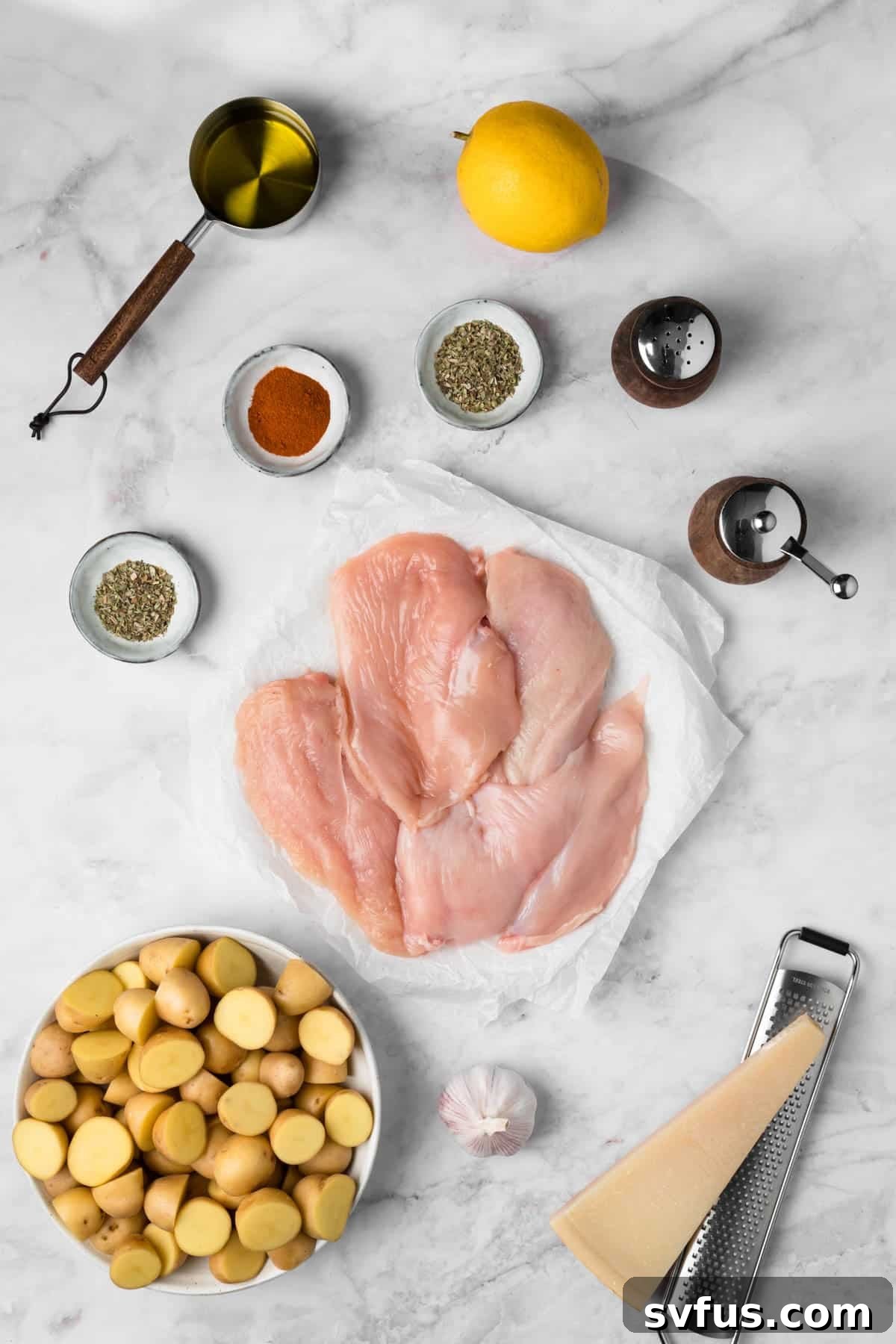 Overhead view of the fresh, vibrant ingredients for sheet pan chicken and potatoes arranged neatly in individual bowls on a rustic wooden surface, ready for preparation.