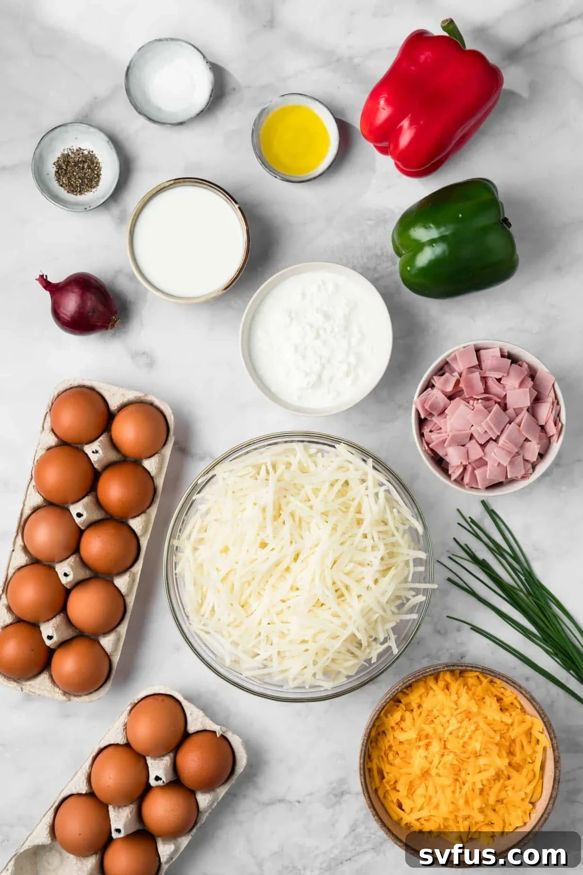 Overhead view of fresh ingredients neatly arranged on a counter for a crockpot breakfast casserole, including eggs, bacon, vegetables, and hashbrowns.