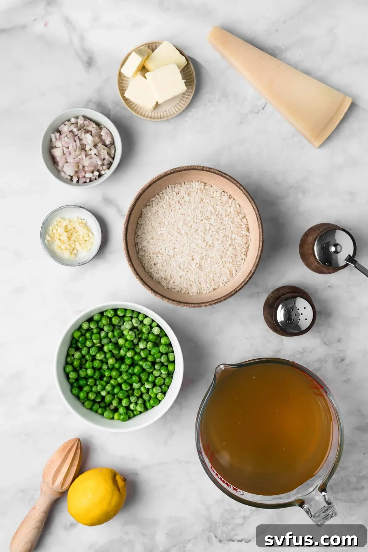 Overhead view of all the fresh ingredients laid out for baked risotto, including Arborio rice, peas, lemon, and stock.